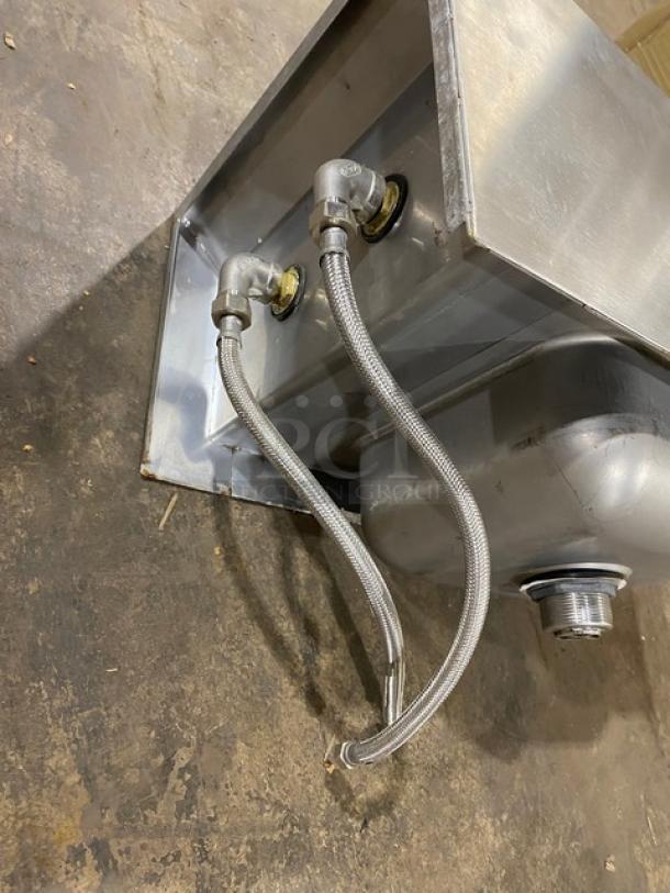 Stainless steel sink with attached plumbing fixtures, showing braided hoses and fittings; appears in good condition.