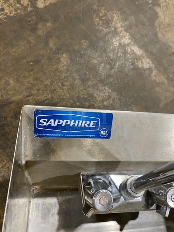 Stainless steel sink with "Sapphire" label and NSF certification, featuring dual chrome faucets.