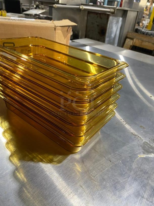 Stack of amber-colored glass trays, rectangular, mint condition, with a cardboard box in the background on a metal surface.