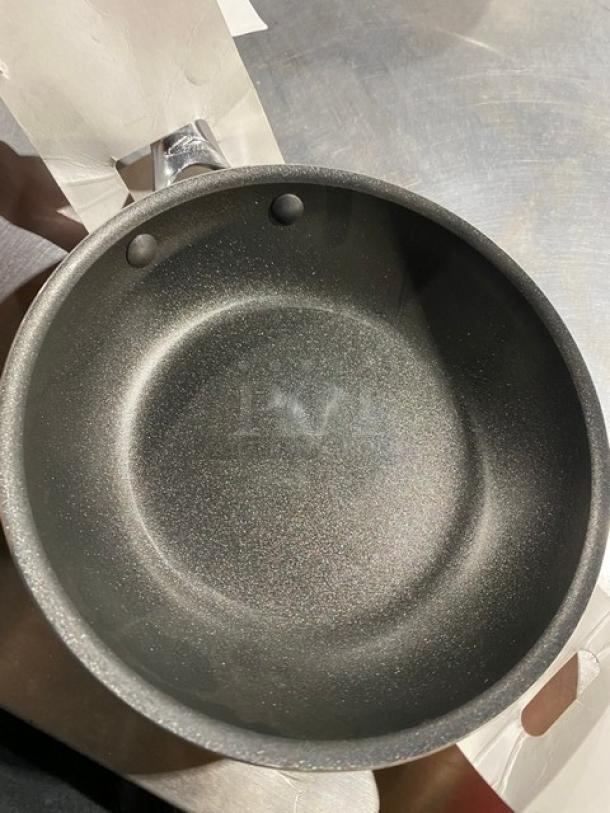 Non-stick frying pan, black, lightly used, with a metal handle. No visible branding or tags. Clean surface.