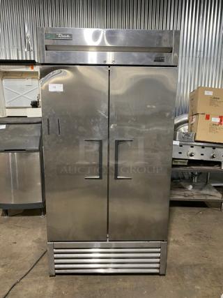Stainless steel commercial refrigerator with two doors and "True" logo. Unit shows some wear, model T-49. Suitable for restaurant use.