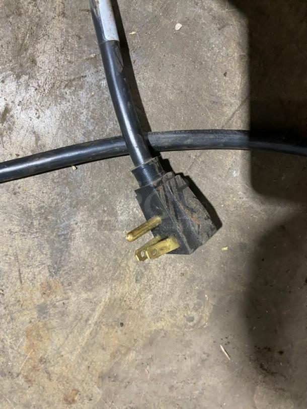 Heavy-duty electrical extension cord with three-prong plug, showing signs of wear and discoloration.