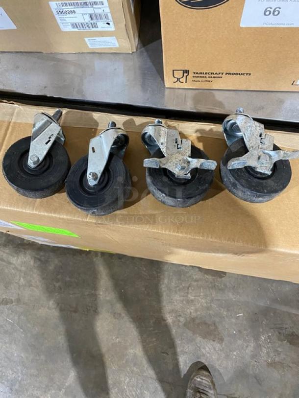 Set of four swivel caster wheels with metal brackets and black rubber tires, lightly used, suitable for heavy-duty equipment.