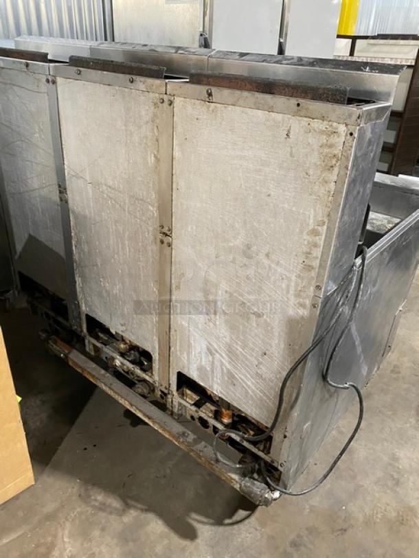 Large industrial metal appliance with visible wiring, showing signs of wear. No labels or markings visible.