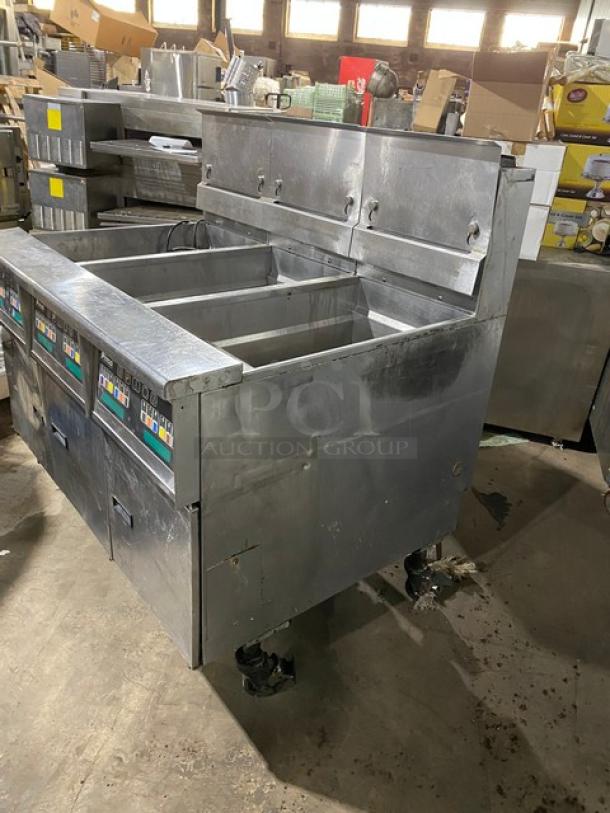 Commercial stainless steel fryer with four baskets, used condition, visible control panels, on wheels. Ideal for restaurant use.