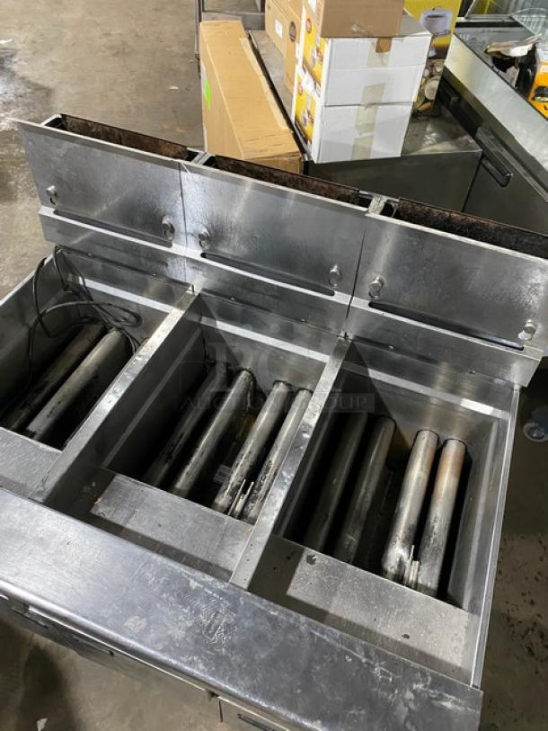 Commercial stainless steel hot dog roller grill with three cooking zones, showing signs of wear, suitable for large-scale food service.