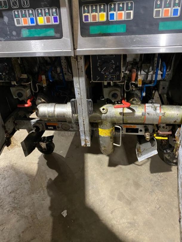 Vintage fuel pump mechanisms, dual units with gauges and control panels. Visible wear, rust, color-coded labels indicate functions.