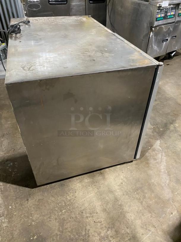 Commercial stainless steel freezer, used condition, with noticeable surface wear and marks.