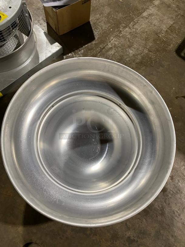 Large industrial stainless steel bowl, circular with concentric ridges, in good condition, placed on a workshop floor.