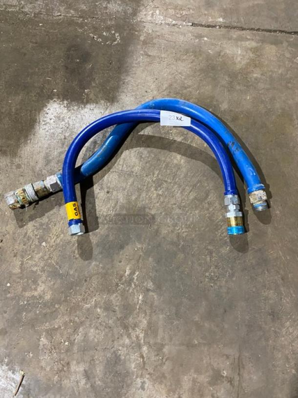 Two blue hydraulic hoses with metal fittings, labeled "23 XL" and "GAZ," moderate wear.