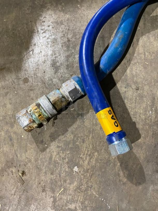 Blue gas hose with metal fittings, labeled "GAS" in yellow. Slightly worn condition, showing rust on connectors.
