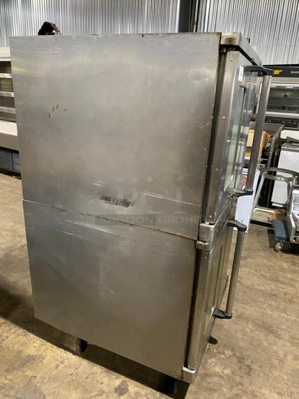 Double-door commercial stainless steel refrigerator. Visible scratches, minor dents. Equipped with glass door panels.