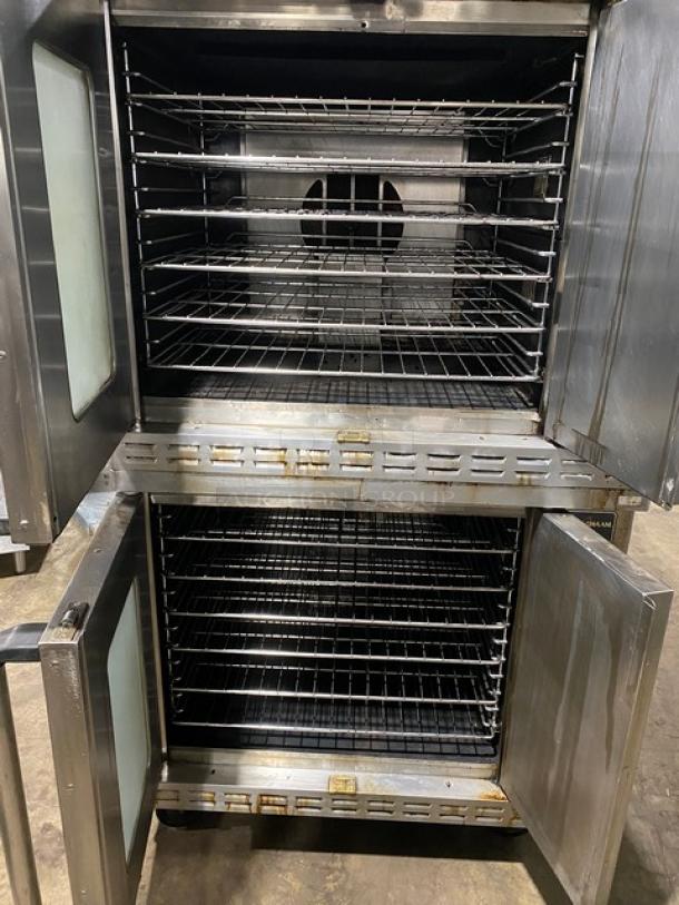 Double-stacked stainless steel commercial oven with multiple racks, open doors, and glass paneled doors. Used condition.