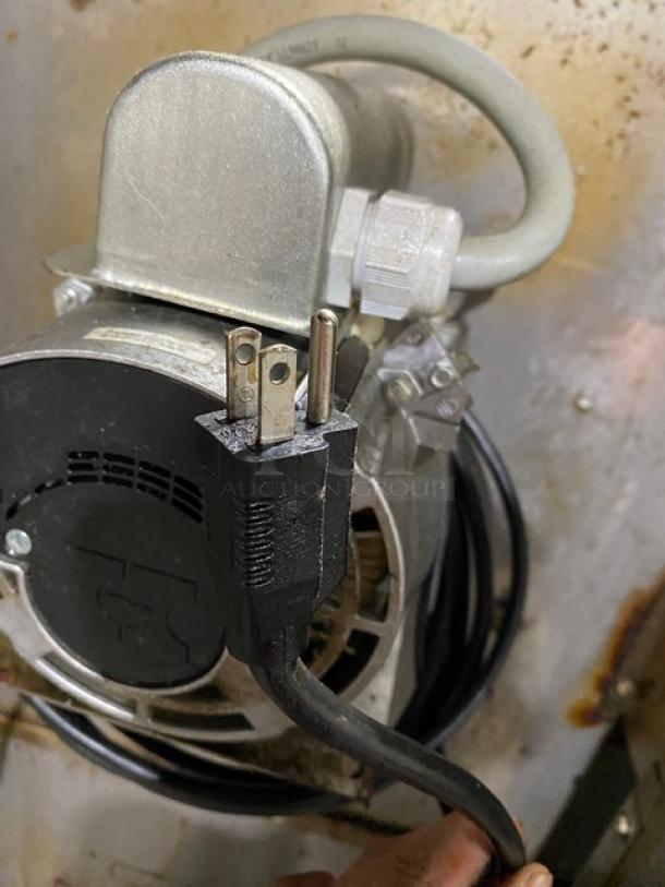 Industrial motor with power plug, robust metal casing, visible wiring. In used condition with minor wear. No visible brand labels.
