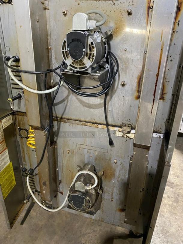 Industrial machine panel with visible wiring and metal frame, showing signs of rust. Includes motor components and labeled yellow tag.