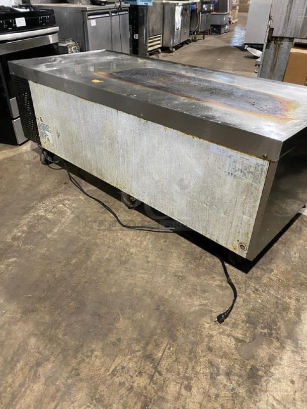 Commercial stainless steel refrigerated counter, scratched surface, visible rust, power cord attached; labels indicate model and specs.