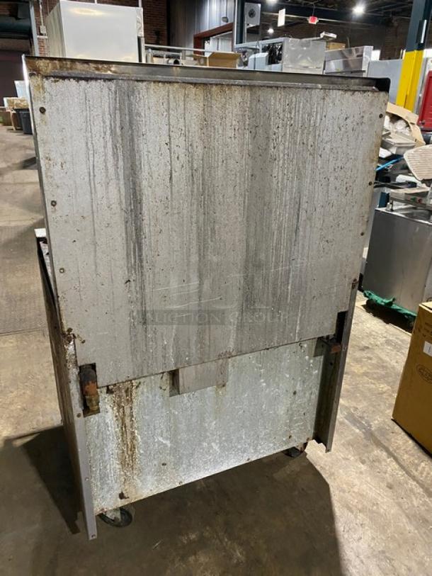 Industrial metal equipment with visible rust and wear, on wheels for mobility, suitable for scrap or restoration project.