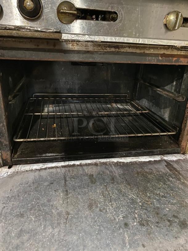 Vintage industrial oven with metal rack, showing signs of heavy use. No markings or labels visible.