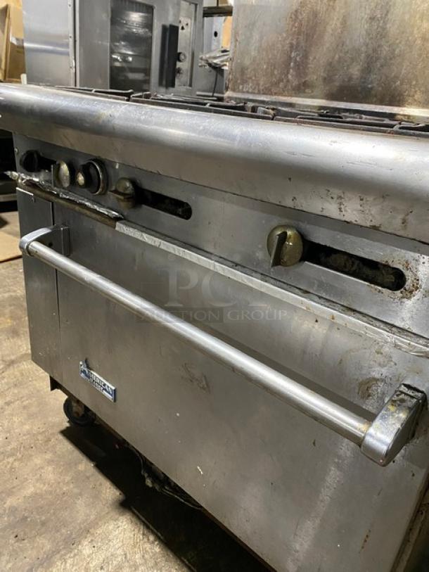Commercial stainless steel oven with stovetop, used condition showing wear. Brand label indicates American Range.