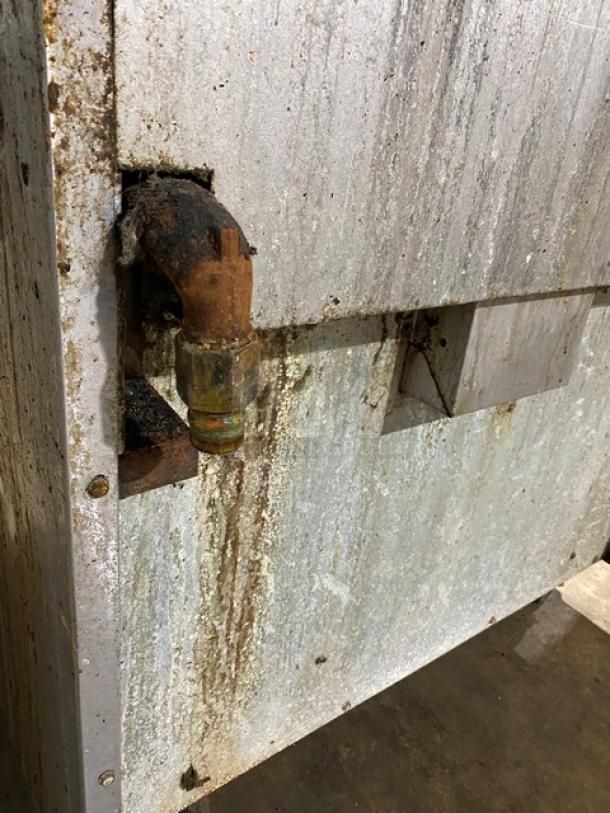 Rusty metal structure with corroded pipe connection, weathered patina, showing signs of age and wear. No visible markings.