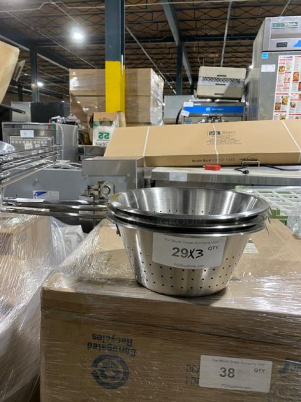 Stainless steel colander with perforated design, stack of three, in warehouse setting. Label reads "29X3 QTY."
