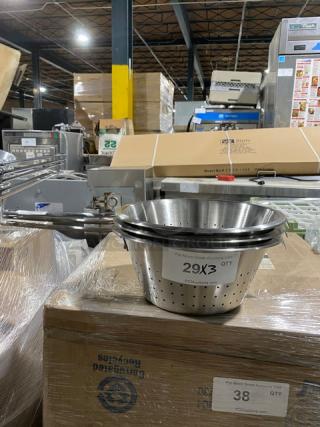 Stainless steel colander with perforated design, stack of three, in warehouse setting. Label reads "29X3 QTY."