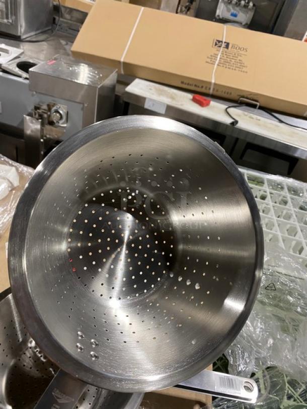 Stainless steel colander, perforated with handles, excellent condition. Packaging visible in background.