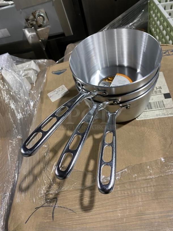 Set of three nested aluminum saucepans with riveted handles, new condition, visible label indicates manufacturer and care instructions.