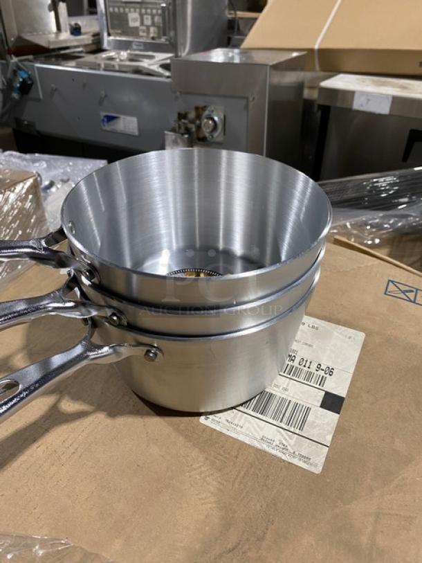 Set of three new aluminum saucepans with riveted handles on a cardboard box, ideal for professional kitchens.