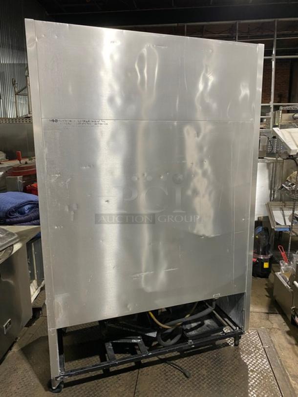 Commercial stainless steel refrigerator unit with visible back panel and exposed wiring. Some surface dents noted.