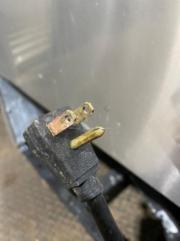 Close-up of a worn, damaged three-prong electrical plug, showing bent and corroded metal prongs.