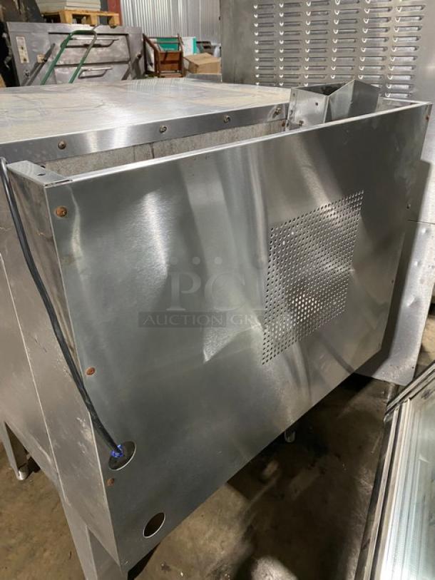 Industrial stainless steel equipment with ventilation panel, visible wiring, and metal finish, showing minor wear.