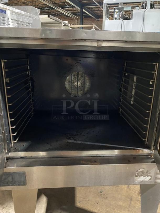 Commercial stainless steel convection oven, front view, visible racks, used condition, no visible labels or tags.
