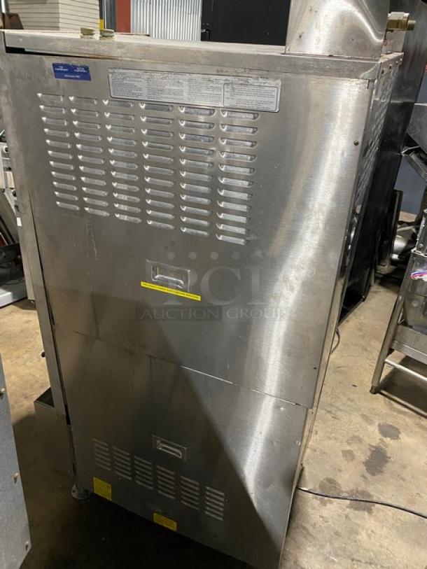 Commercial stainless steel ice machine, showing ventilation grilles and control panel. Slight wear, labels with operating instructions.