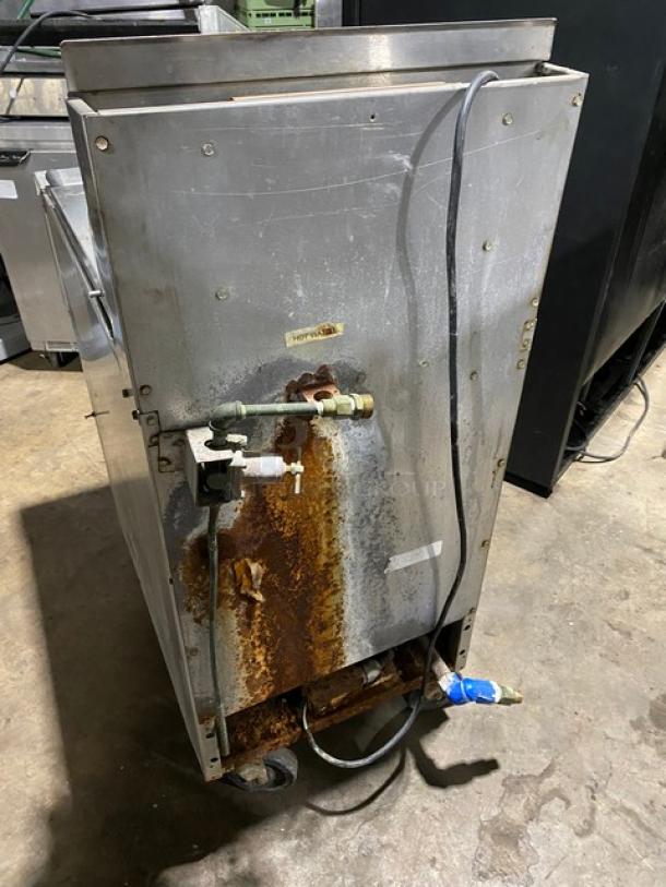 Commercial stainless steel appliance with visible rust and wiring on the back. Worn condition, marked "Hot Water."