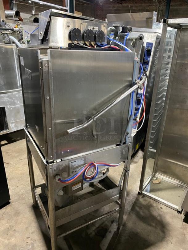 Commercial dishwasher in stainless steel, used condition, with visible wiring and control panel. Model label partially visible.
