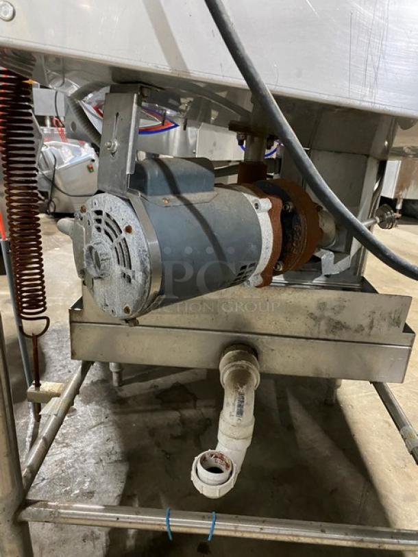 Industrial motor assembly with metal housing, attached to a plumbing setup. Visible wiring and rust on connecting parts.