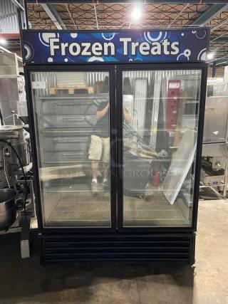 Commercial double-door freezer for frozen treats with glass doors, metal shelving, and "Frozen Treats" signage. Used condition.