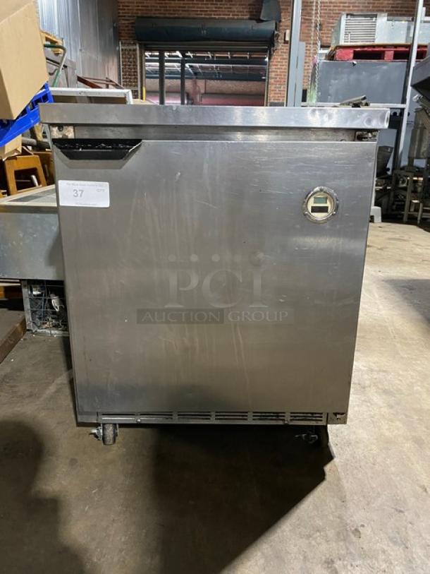 Stainless steel commercial freezer with caster wheels, showing moderate wear. Label marked "37" in white.