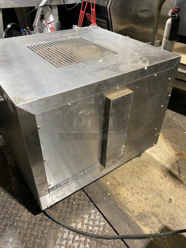 Industrial stainless steel cabinet with ventilation grille, showing signs of wear. Power cable attached. Appears sturdy.