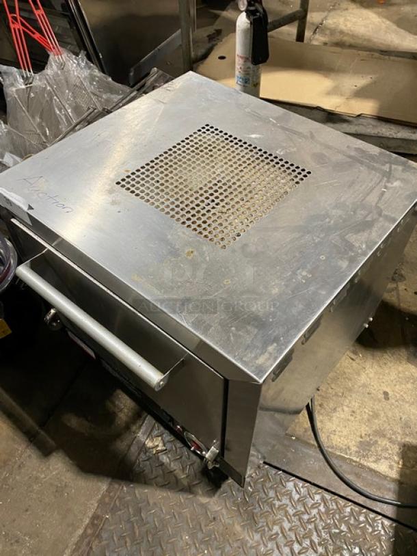 Commercial stainless steel countertop oven with ventilation grate. Used condition, visible markings. Ideal for kitchen use.