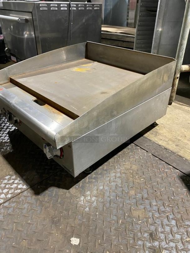 Commercial stainless steel flat-top griddle in used condition, featuring side and rear splash guards and dual control knobs.