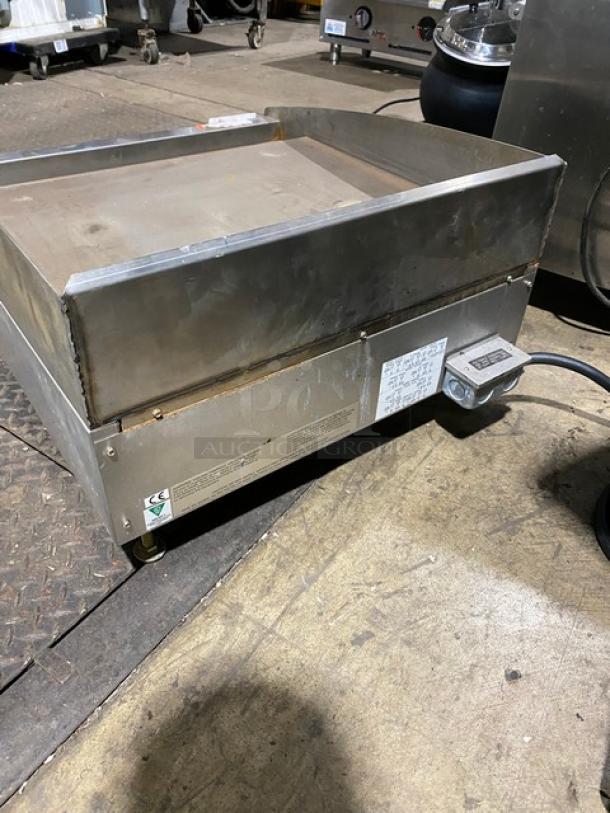 Commercial stainless steel griddle, electric-powered with visible control panel. Signs of wear, includes safety and model labels.