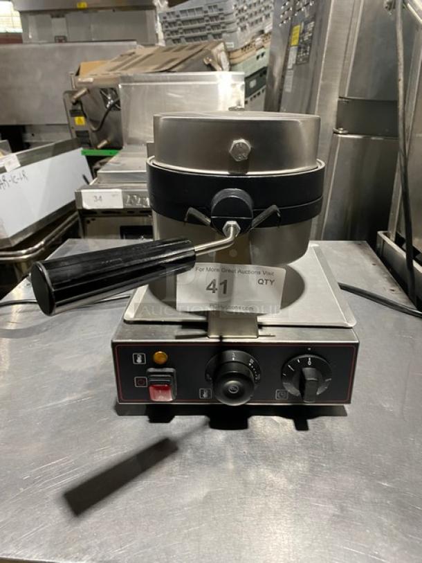 Commercial waffle maker with adjustable knobs, black handle, and silver body. Item number 41 tag visible.