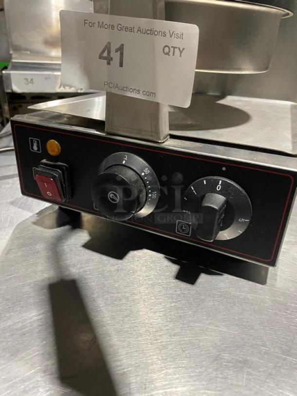Commercial kitchen equipment control panel with temperature and timer knobs, red power switch, and operational markings.