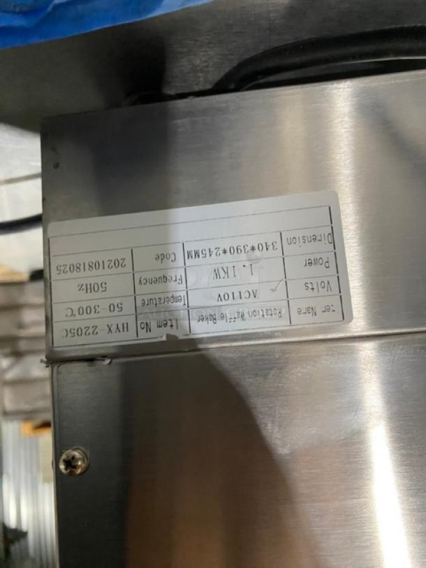 Industrial metal equipment with a label displaying 1kW power, 50 Hz frequency, and item number HXN-2206G. Visible serial code.