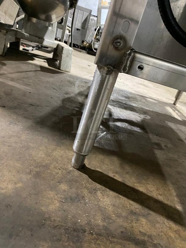 Stainless steel appliance leg, adjustable height, attached to commercial kitchen equipment on concrete floor. Clean condition.