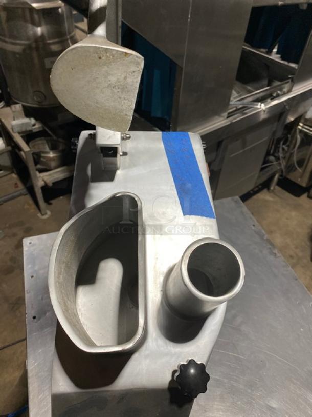 Industrial food processor, metal body, wide chute, visible wear. Blue tape with numbers for identification. Ideal for commercial use.