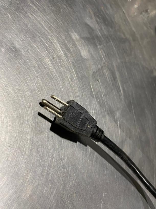 Black electrical power cord with a two-prong plug, showing slight wear, on a metallic surface.