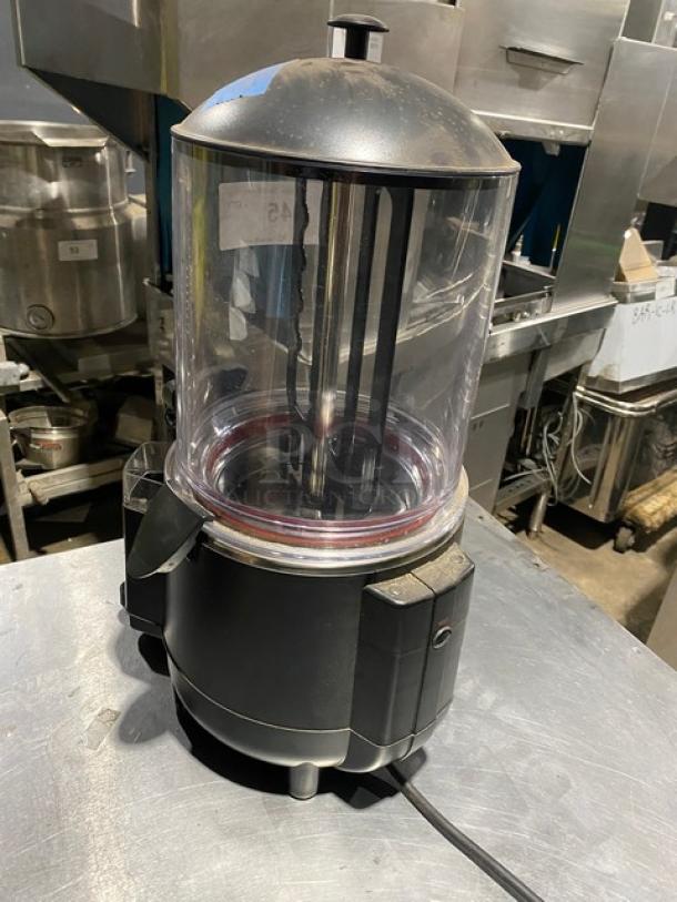 Commercial drink mixer with clear cylindrical container and black base, minor wear, suitable for restaurant use.